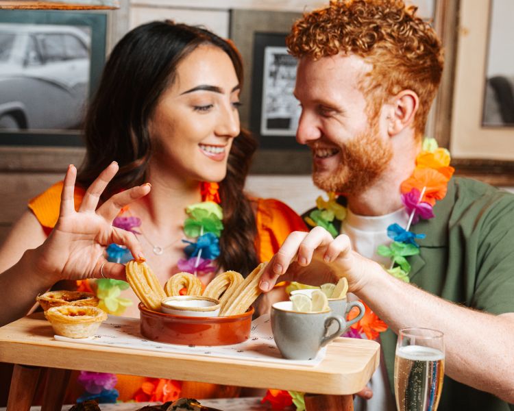 a man and a woman eating churros on a cuban inspired afternoon tea experience