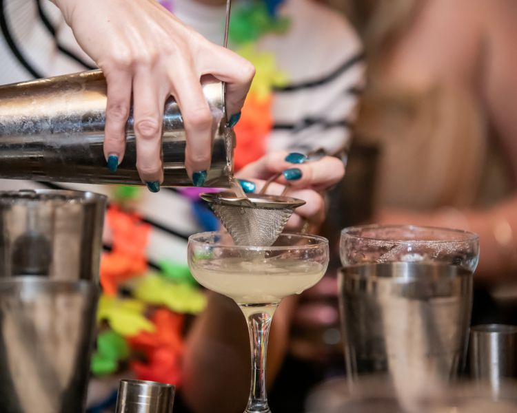 a cocktail being poured into a glass on a cocktail masterclass at revolucion de cuba