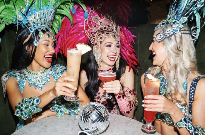 three ladies dressed in rio carnival dress enjoying cocktails at revolucion de cuba