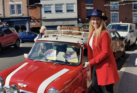 a woman standing next to a classic red mini cooper