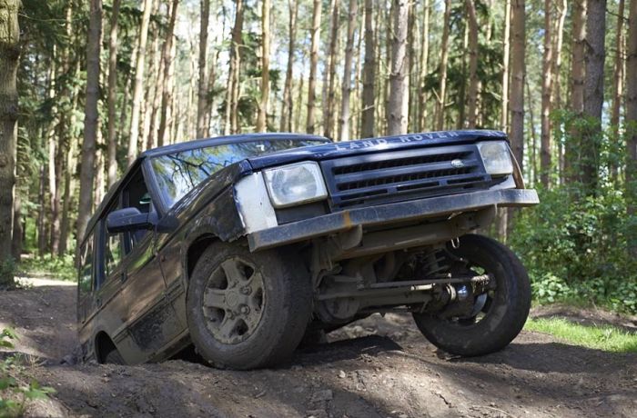 a landrover going up a bank on a woodland course on an off road driving experience