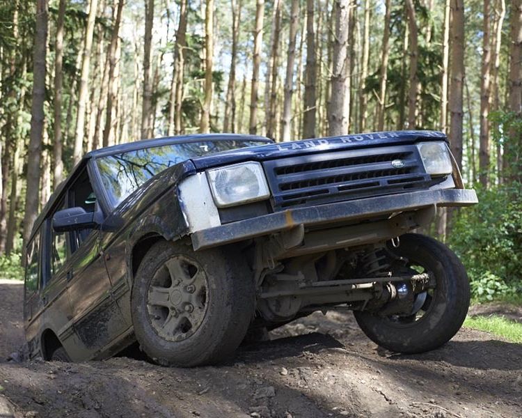 a landrover going up a bank on a woodland course on an off road driving experience
