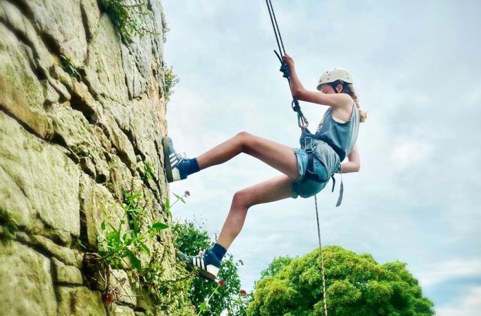 a girl abseiling down a rock face in wales