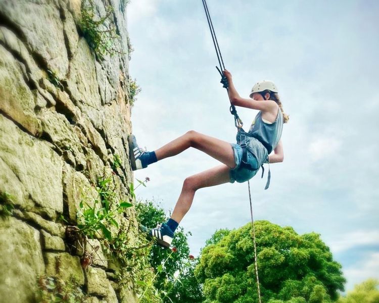 a girl abseiling down a rock face in wales