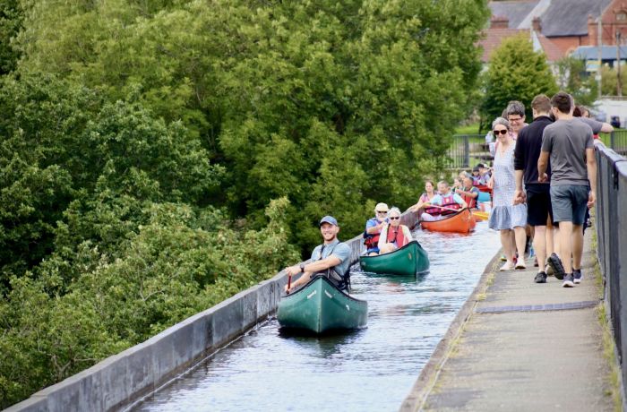 people in canoes going along an aqueduct in wales
