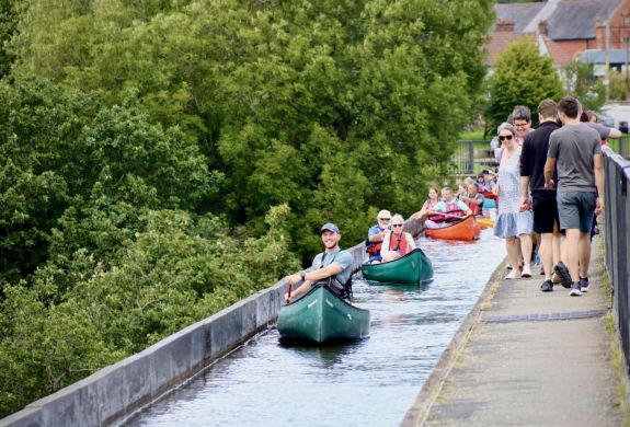 people in canoes going along an aqueduct in wales