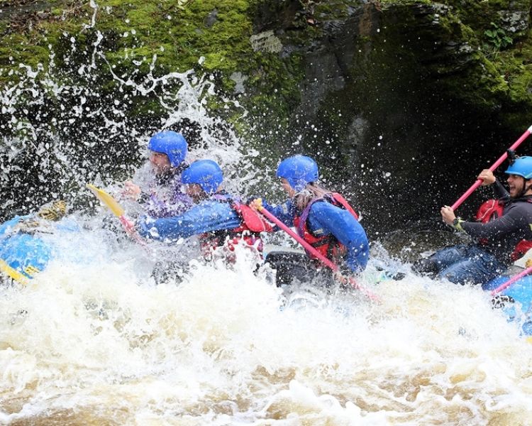 People whitewater rafting on a river in wales