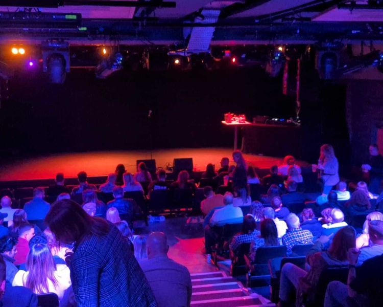an audience finding their seats ready for a comedy night
