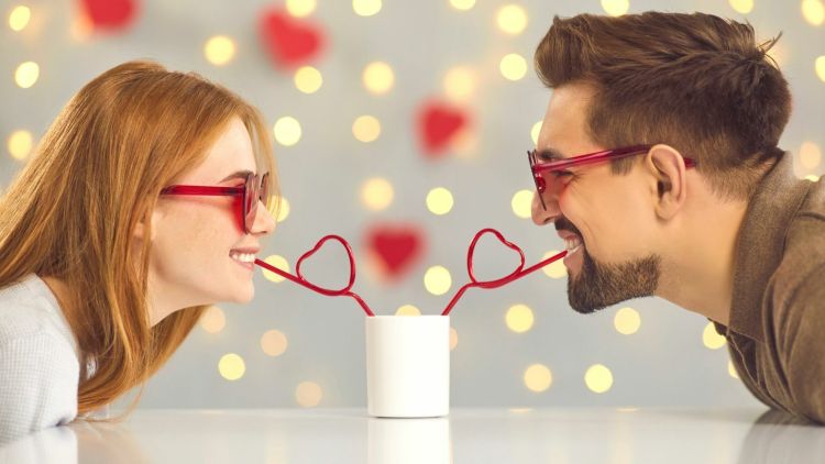 Man and woman drinking through heart shaped straws