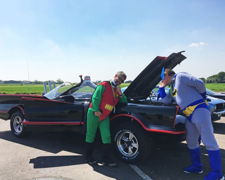batman and robin next to the batmobile on a track for a superhero driving experience day