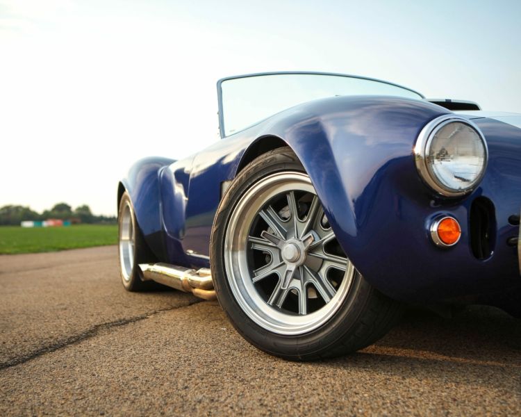 a close up of the front of a blue vintage sports car on a track as part of a driving experience day
