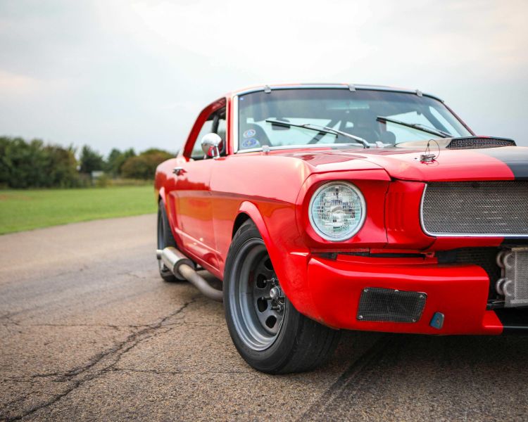 a close up of the front of a red and black vintage sports car on a track as part of a driving experience day