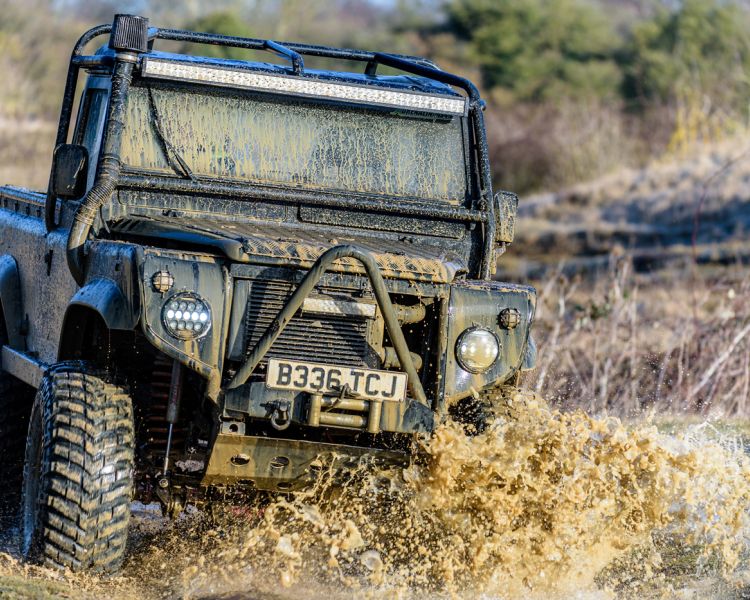 a mad max inspired land rover driving through muddy puddles on a driving experience day