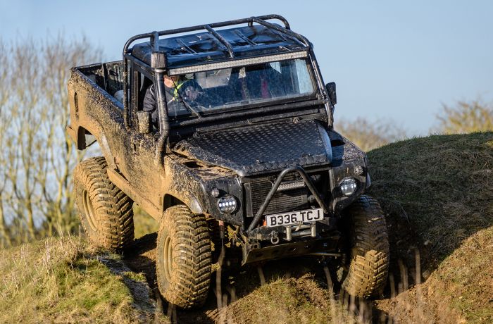 a mad max inspired land rover driving off road down a hill on a driving experience day