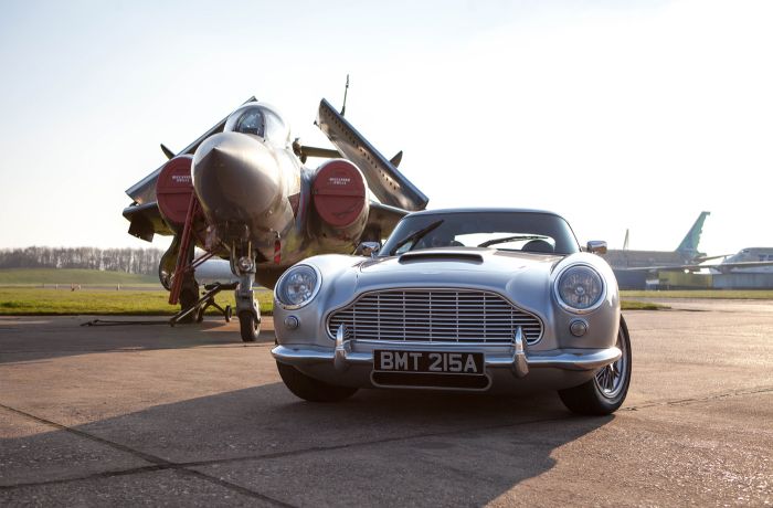 a british classic car next to an airplane on an airfield track