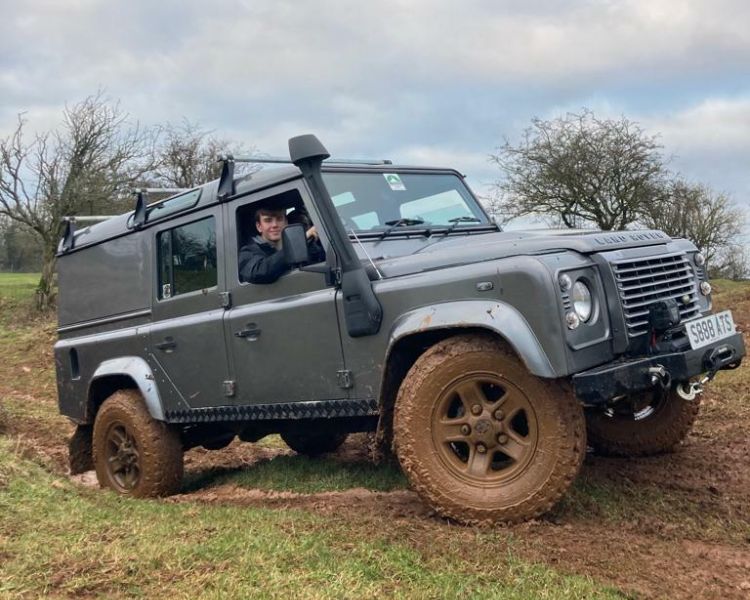 a 4 x 4 land rover driving up a muddy slope as part of an off road driving experience