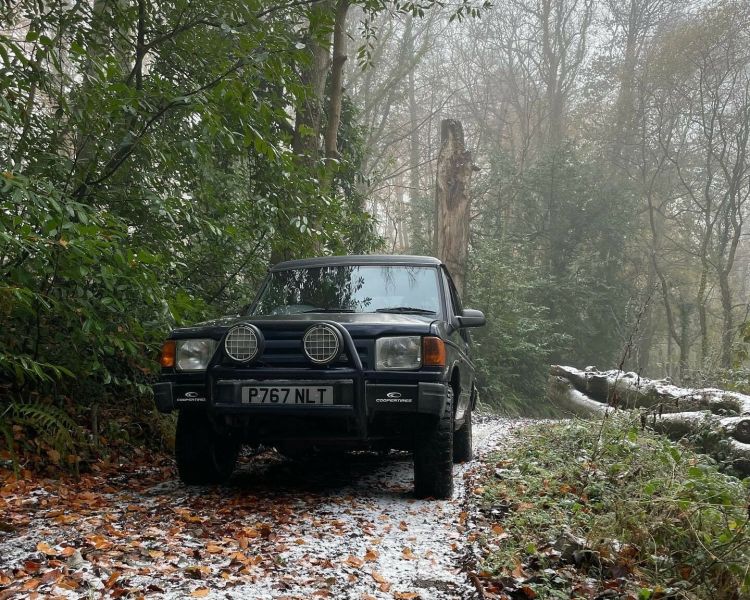 a land rover driving up a muddy slope through the woods as part of an off road driving experience in Devon