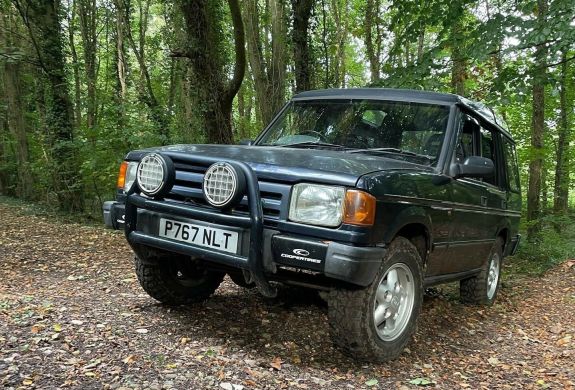 a land rover driving up a slope in a wooded area as part of an off road driving experience in Devon