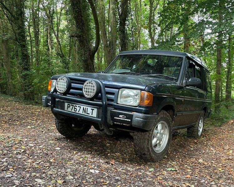 a land rover driving up a slope in a wooded area as part of an off road driving experience in Devon