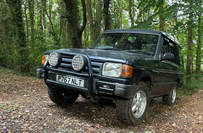 a land rover driving up a slope in a wooded area as part of an off road driving experience in Devon