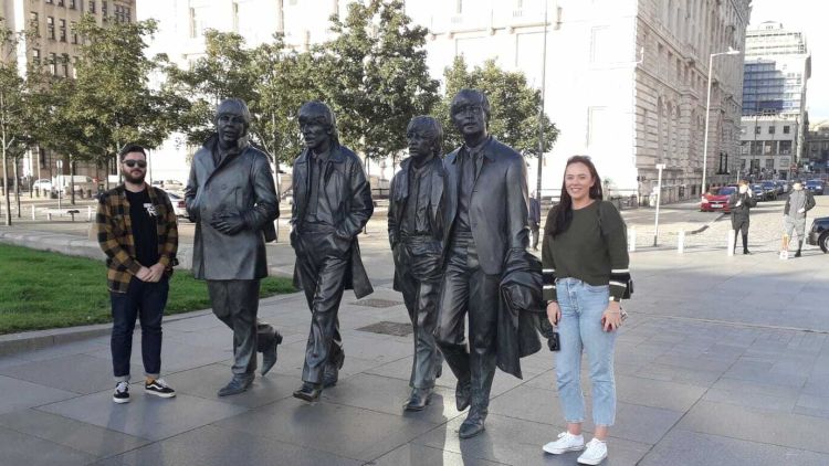 people posing with statues of the beatles seen on the beatles walking tour in liverpool