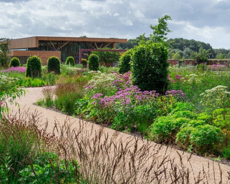 a winding path through the gardens at rhs bridgewater near manchester with a view of the welcome centre