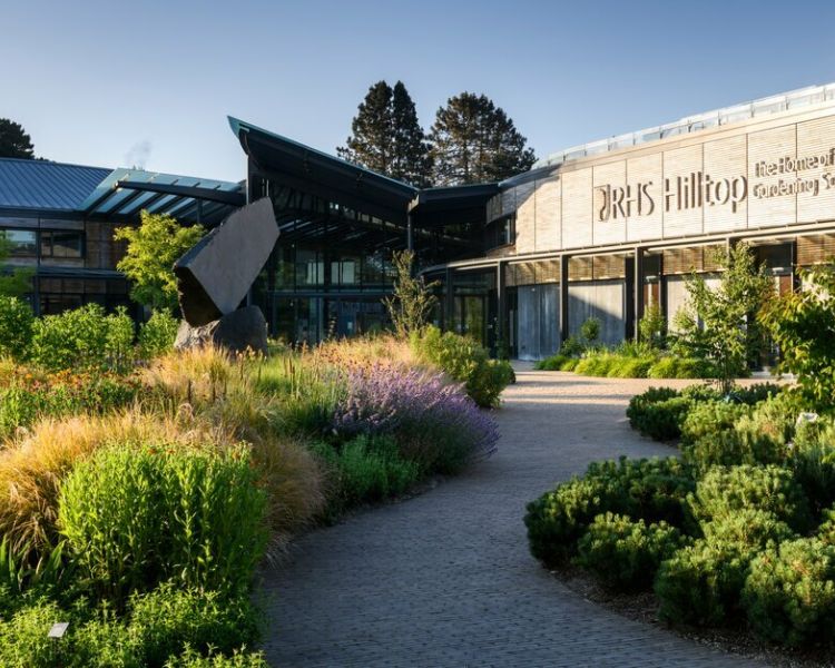 view of the gardens at rhs wisley and the rhs hilltop building