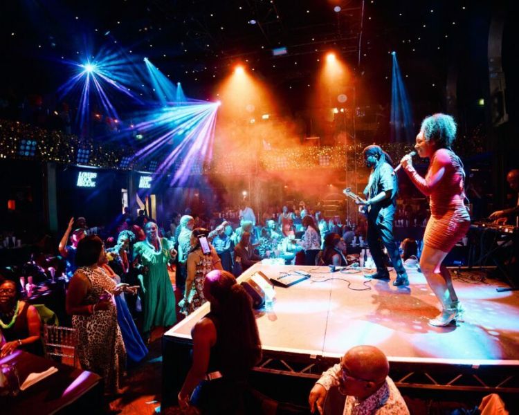 singer and musicians on stage with people dancing at a reggae live music show