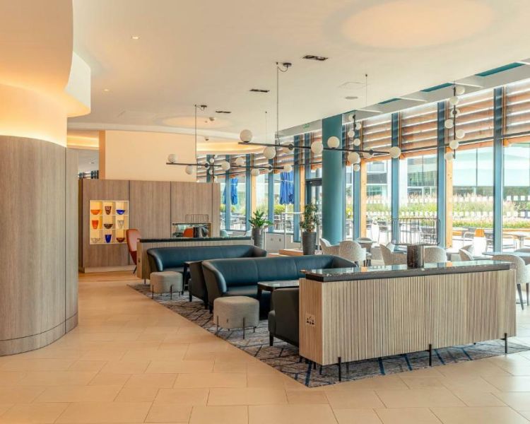 the indoor seating area at a hotel with high windows looking out onto the terrace area