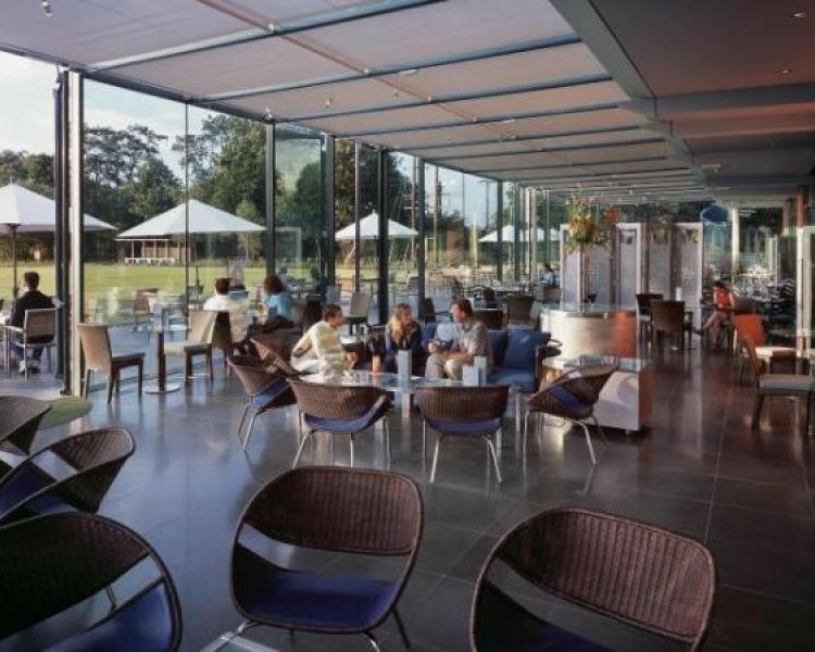 the conservatory area filled with tables and chairs at the crowne plaza hotel in marlow