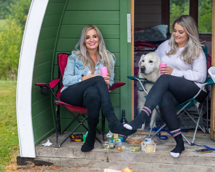 2 ladies and a dog sat outside a pod