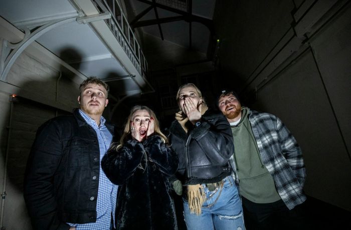 four young people looking scared on a ghost tour of a prison