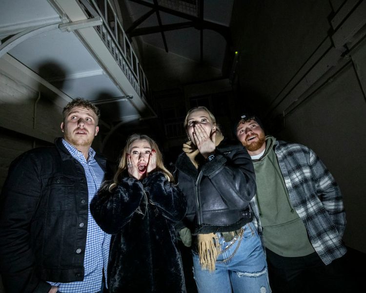 four young people looking scared on a ghost tour of a prison