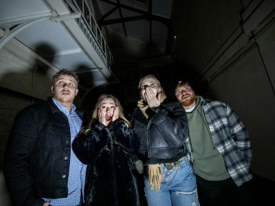 four young people looking scared on a ghost tour of a prison