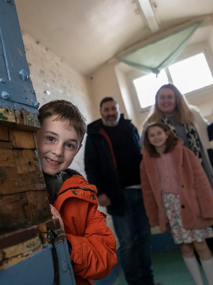 a family looking in one of the cells on a self guided tour of a former prison