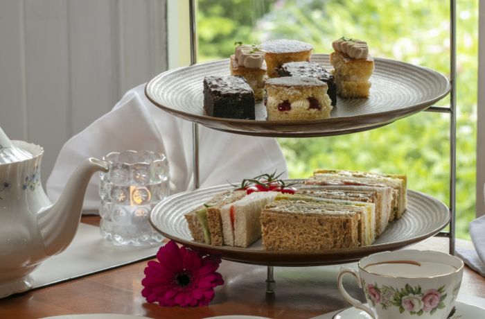 an afternoon tea set up on a cake stand with cups of tea on a table in front of a window at a hotel in ironbridge in shropshire