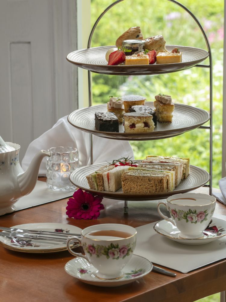 an afternoon tea set up on a cake stand with cups of tea on a table in front of a window at a hotel in ironbridge in shropshire