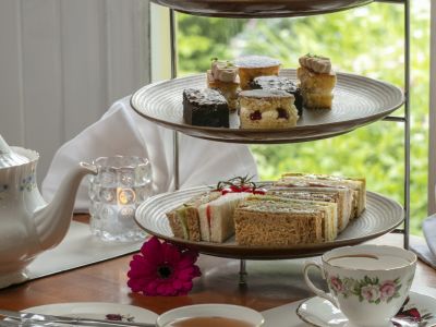 an afternoon tea set up on a cake stand with cups of tea on a table in front of a window at a hotel in ironbridge in shropshire