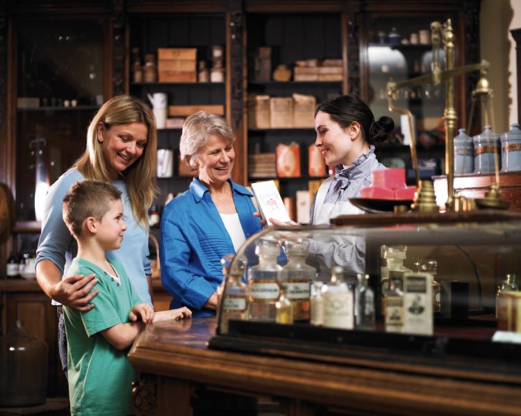 a family visiting a victorian shop at blists hill victorian town, an attraction in ironbridge in shropshire