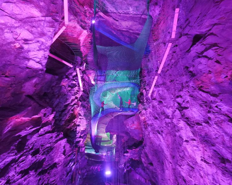 the trampolines built inside caverns at zip world bounce below lit up in pink