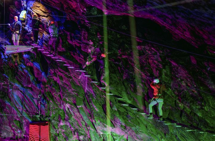 people climbing a ladder staircase underground in zip world caverns