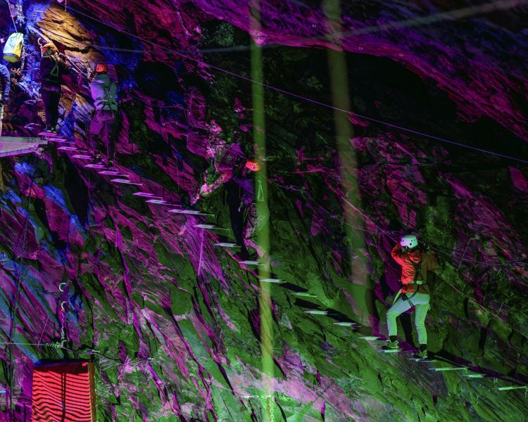 people climbing a ladder staircase underground in zip world caverns