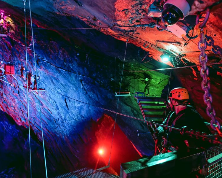 a view of the zip world caverns course underground lit up in different coloured lights