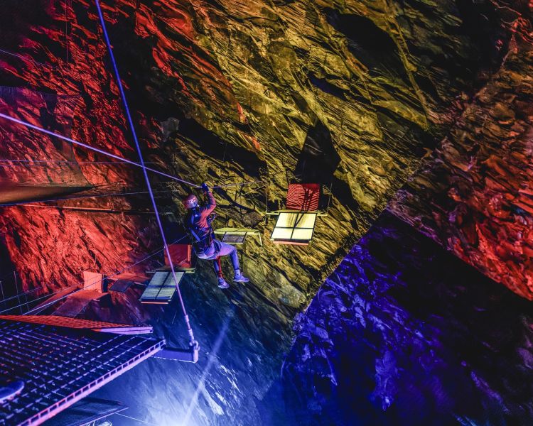 a person going down a zip line underground in zip world caverns