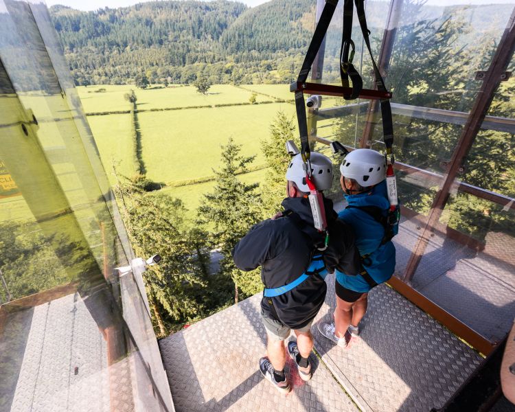 two people standing at the top of zip world plummet ready to drop