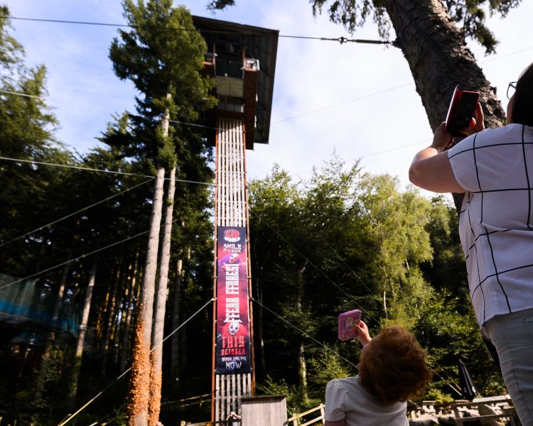 people on the ground looking up to the top of zip world plummet