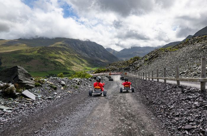 two people on the dirt track at zip world quarry karts with mountains in the background