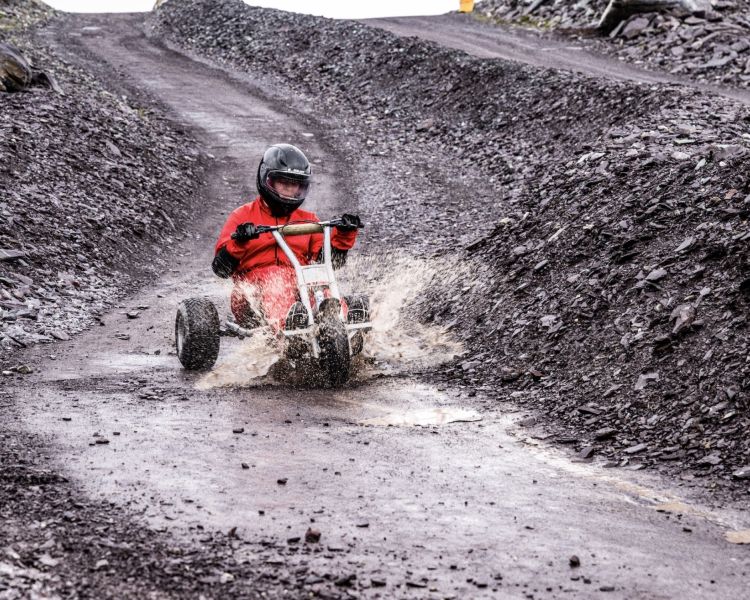 person going down the dirt track at zip world quarry karts splashing through puddles
