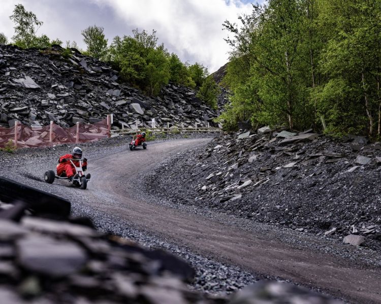 two people coming down the dirt track at zip world quarry karts