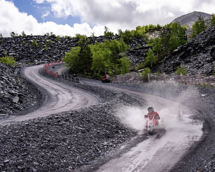 person on the dirt track at zip world quarry karts going through a puddle with water splashing up